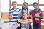 Smiling school kids standing with arm around in library