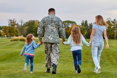 family walking. Soldier at vacation. Four family members walking together holding hands.