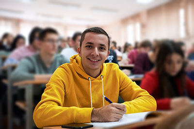 student taking notes while studying in high school. Portrait of college guy writing while completing assignment.