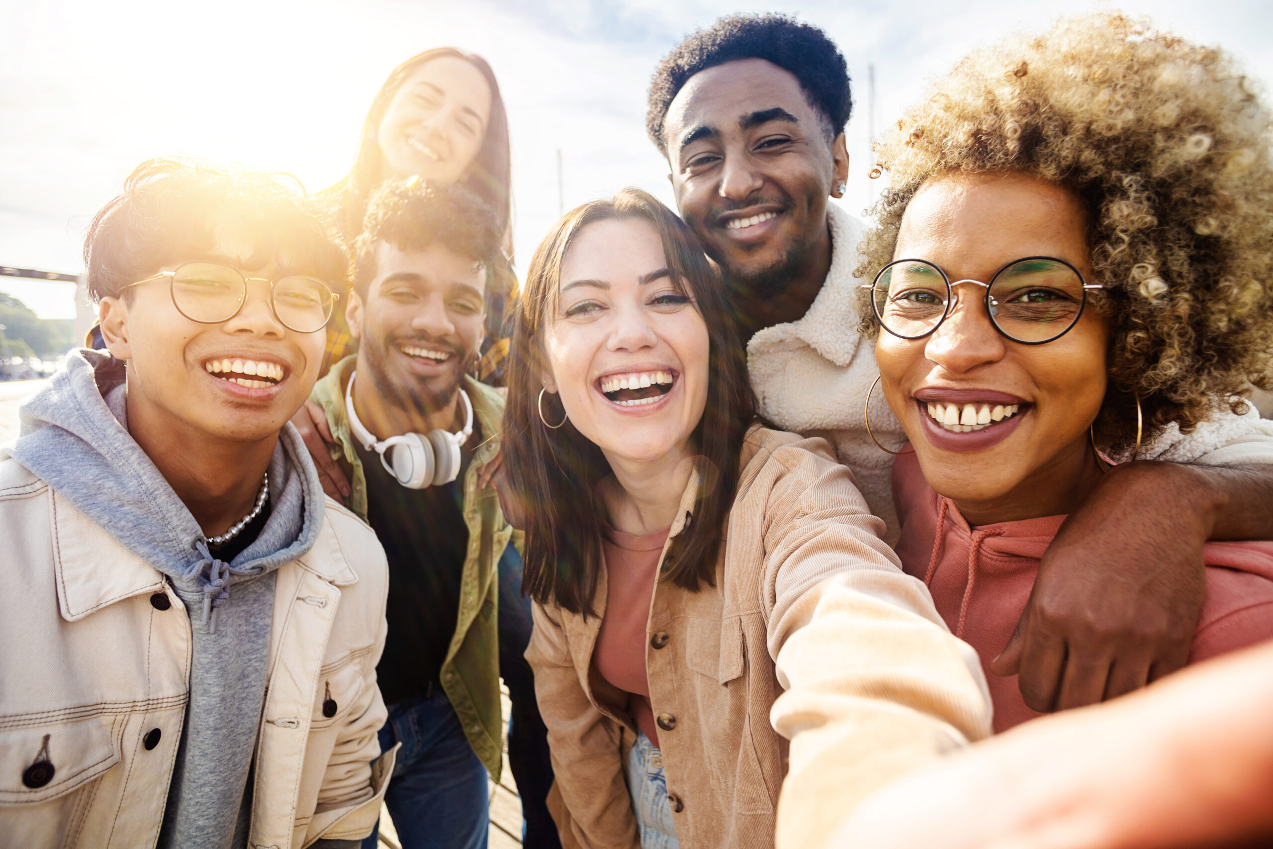United group of happy young friends having fun while taking a selfie with mobile phone outdoors - Diverse group of millennial people laughing together