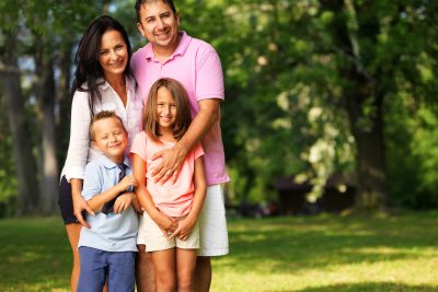 happy family of four posing outside