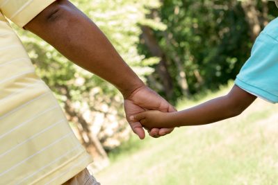 Rear view of father and son holding hands.